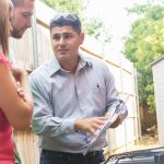 Air Conditioner repairman explaining cost of repairs to homeowners